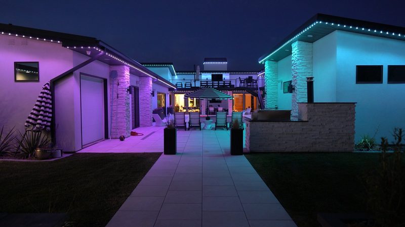 A modern home lit in teal and purple