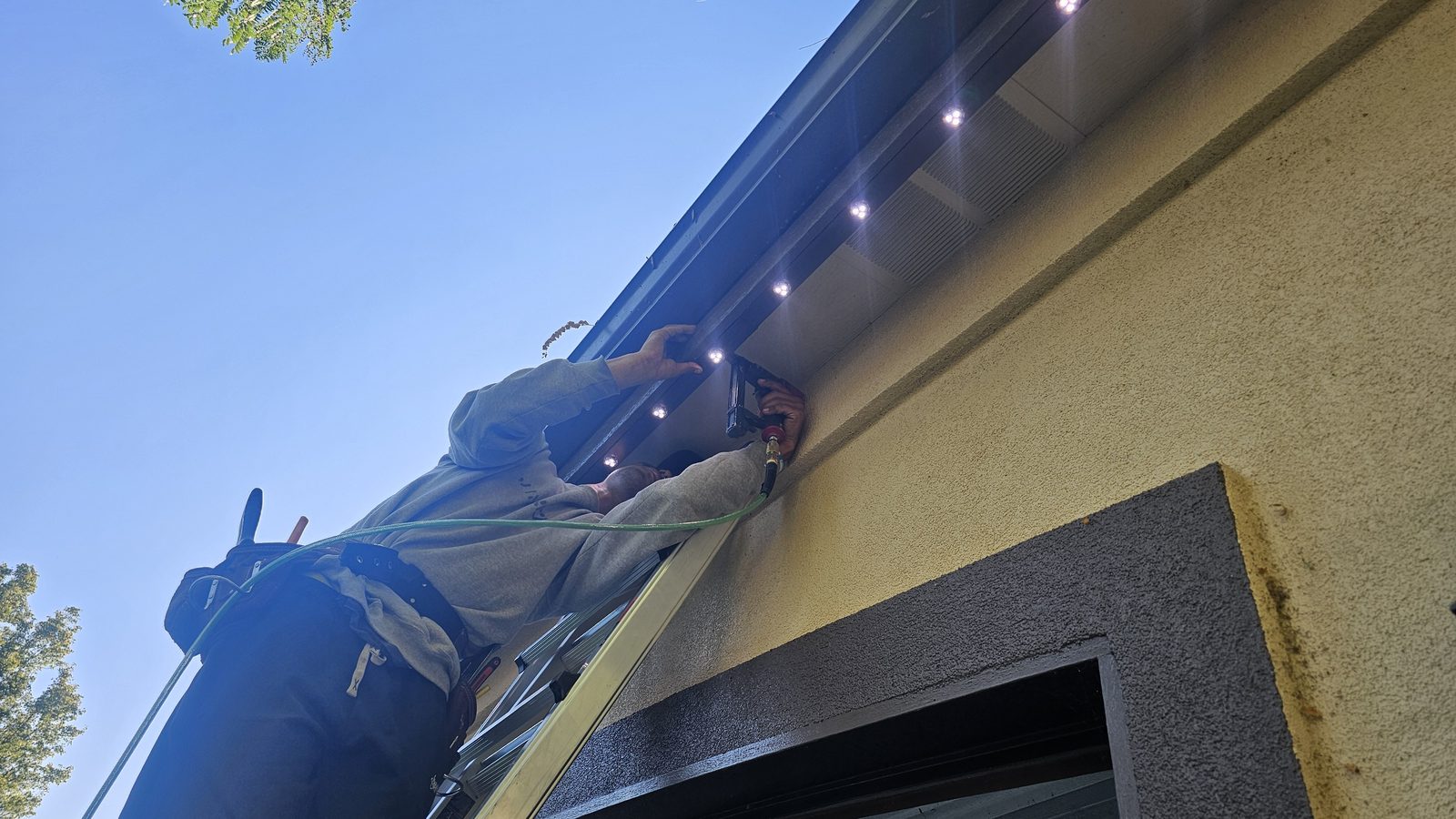An installer seating lights into the track under a soffit on a stucco wall